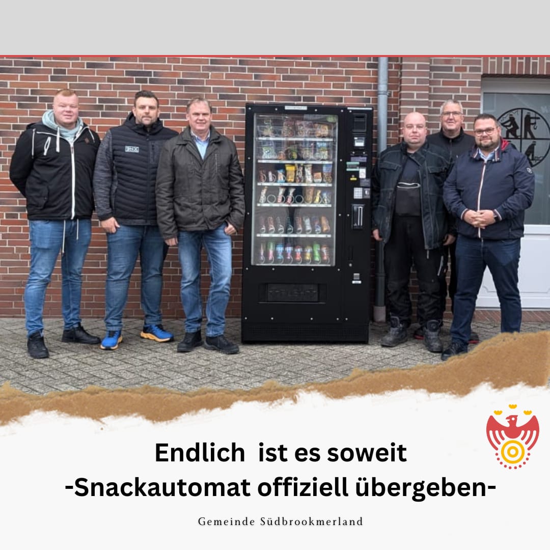 Mehrere Personen stehen neben einem Snackautomaten und lächeln in die Kamera