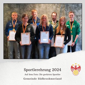 Mehrere Personen tragen jeweils eine Medaille um den Hals, eine Urkunde in den Händen und lächeln in die Kamera